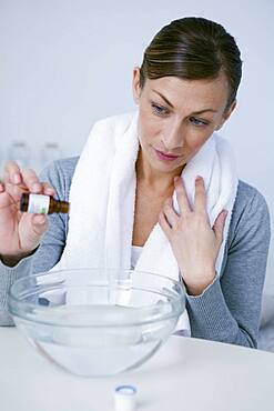 Woman preparing inhalation with essential oil.