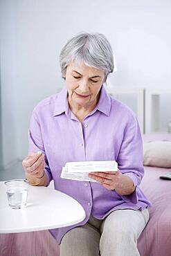 Senior woman reading medication instruction sheet.