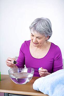 Senior woman preparing inhalation with essential oil.