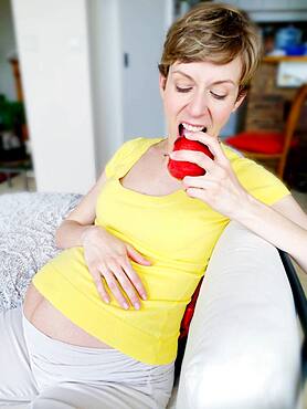 Pregnant woman eating an apple.