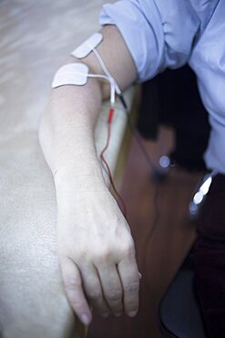 Female patient arm in physiotherapy rehabiliation treatment from injury in hospital clinic with electrical stimulus attached with plaster.