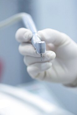 Dental instrumentation. Dental cleaning tool in the hand of dentist in dentists surgery clinic. Artistic color photo with low depth of focus.