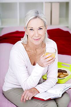 Senior woman drinking orange juice.