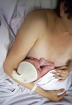 In the delivery room, skin to skin contact and first attempt at breast-feeding.