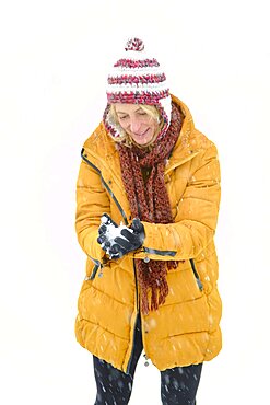 Caucasian young woman making a snowball outdoor in winter time. Navarre, Spain, Europe.