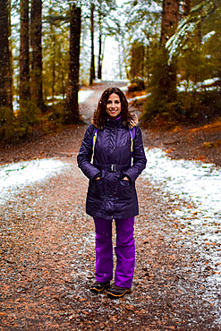 Contemplative attractive young caucasian female hiker in the snowy mountains of the Pyrenees during winter season, Aragon, Spain