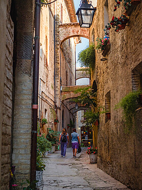 Two people walking in a street in Old town, Bevagna, Umbria, Italy, Europe