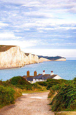 Coastguard cottages at Cuckmere Haven, with the white cliffs of Seven Sisters and Beachy Head in the background, Seaford, East Sussex, England