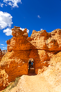 Tourists entering natural arch while hiking Queens Garden Trail, Bryce Canyon National Park, Utah, USA