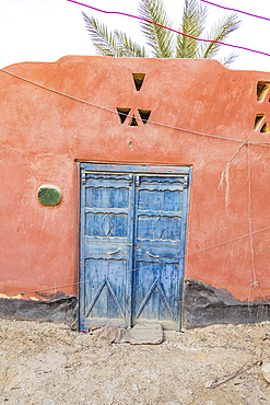 Faiyum, Egypt. Blue painted doors in a wall in the village of Faiyum.