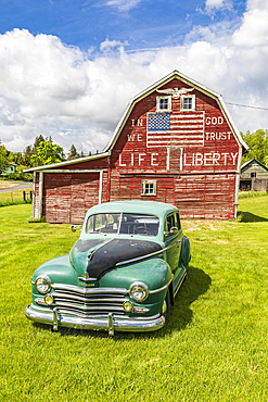 Latah, Washington, USA. May 24, 2021. Vintage Plymouth Super De Luxe automobile and a weathered red a barn. Editorial Use Only