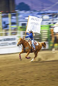 USA, Washington State, Whitman County. Palouse. Palouse Empire State Fair. Colfax. September 9, 2021. Woman riding with flag at a rodeo.