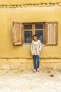 Faiyum, Egypt. February 19, 2022. Girl leaning on a building in the village of Faiyum.