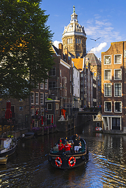 Basilica of St. Nicholas in Amsterdam and canals with a boat during sunset, Netherlands, North Holland, Western Europe