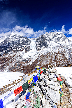 Vertical View of Prayer Flags and Stone Cairn on Snow-Draped Kyanjin Ri Summit Overlooking Langtang Glacier and Himalayan Peaks