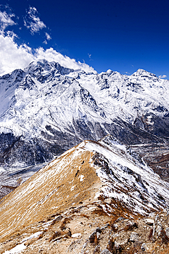 Narrow snow-covered ridge trail ascending toward Kyanjin Ri with panoramic views of Langtang Himal and Scout Peak, Langtang National Park, Nepal