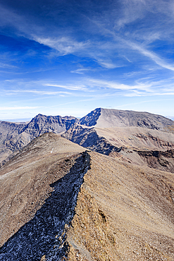 View from the summit of pico de la veleta over mountain ridges leading towards Mulhacen and Alcazaba in the Sierra Nevada, Spain