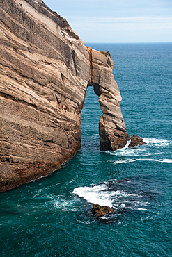 Natural sea arch carved into coastal cliffs by the Tasman Sea at Cape Farewell, South Island, New Zealand.