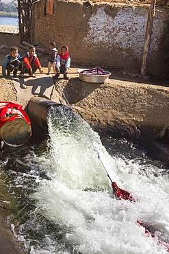 Washing out of the drain pumping water from the Nile to supply a crop irrigation channel around the village of Ramadi, west bank of the Nile south of Edfou, Egypt, North East Africa