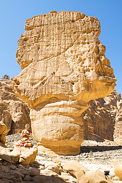 Woman practicing yoga poses among sandstone rock formation in the desert canyons of the Ashar Valley, Medina Province, Saudi Arabia, Middle East