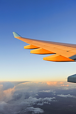In-flight airliner wing seen through the window at sunset