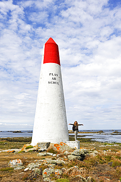 Young girl standing beside a seamark on Ile de Sein,off the coast of Pointe du Raz,Finistere department,Brittany region,west of France,western Europe