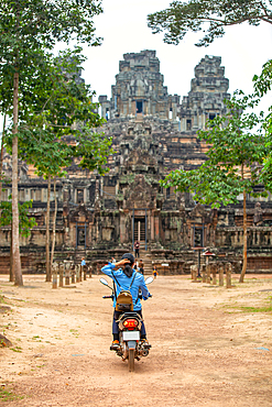 A unidentifed woman riding a scooter towards Banteay Kdei temple in Angkor complex, UNESCO World Heritage Site, Cambodia, Indochina, Southeast Asia, Asia