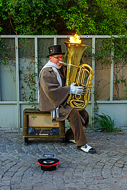 Busker with tuba blowing flames on a wintry day