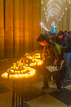 Woman lighting a candle in cathedral Notre Dame