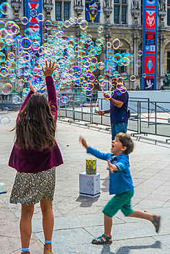 Children chasing bubbles, in daytime, in Summer