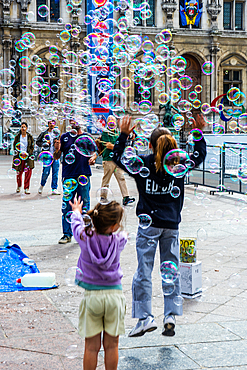 Children chasing bubbles, in daytime, in Summer