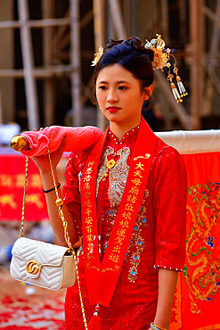 Young women in elegant Chinese dresses carrying celebration banners in a parade in Puning City, Guangdong Province, China.