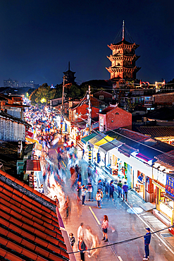 Busy pedestrian street with the twin pagodas of Kaiyuan Temple in the background. Quanzhou: Emporium of the World (UNESCO World Heritage), Fujian, China