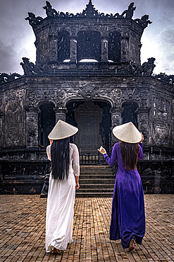 Women in ao dai dress and conical hat walking to Khai Dinh Mausoleum, Hue, Central Vietnam. (MR)