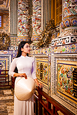 Woman in a white ao dai dress looking at carvings, Khai Dinh Tomb, Hue, Central Vietnam. (MR)