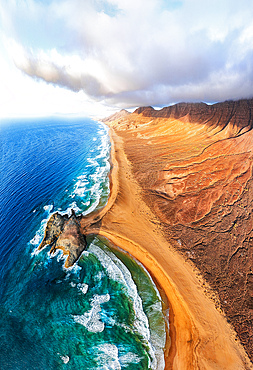 Aerial view of volcanic cliffs overlooking Cofete beach washed by waves, Jandia Nature Park, Fuerteventura, Canary Islands, Spain