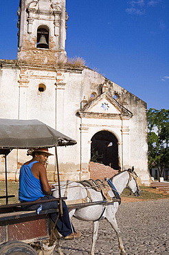 A man with horse and buggy passing an old church in Trinidad, Cuba, West Indies, Central America