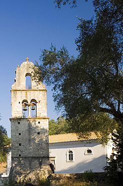 The stone belltower of Agios Constantinos surrounded by olive trees, Paxos, Ionian Islands, Greek Islands, Greece, Europe