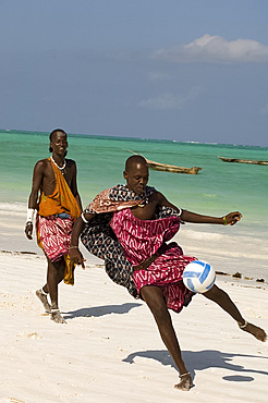 Maasai tribesmen in colourful native dress playing football on the beach, Paje, Zanzibar, Tanzania, East Africa, Africa