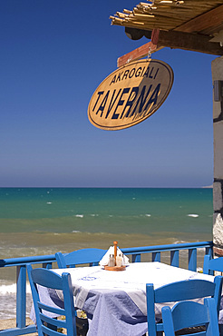 A taverna table overlooking the sea in Kalives on the North coast of Crete, Greek Islands, Greece, Europe