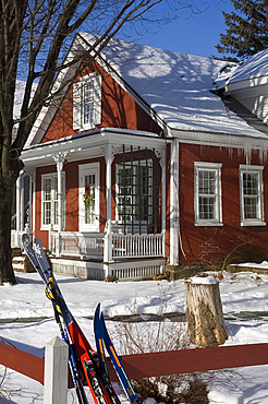 Skis leaning on a fence in front of a colourful red house in Stowe, Vermont, New England, United States of America, North America