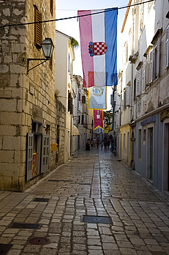 Medieval flags and stone paving in the main shopping street, Srednja Street, Rab Town, island of Rab, Kvarner region, Croatia, Europe