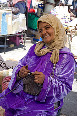 A woman in traditional dress knitting wool hats in the souk, Marrakech, Morocco, North Africa, Africa