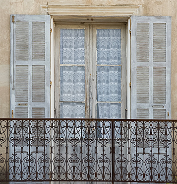 An old window, iron balcony and lace curtains in the picturesque village of Aregno in the inland Haute Balagne region, Corsica, France, Europe