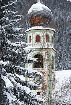 The bell tower of the Church of San Casiano surrounded by snow covered trees, Dolomites, South Tyrol, Italy, Europe