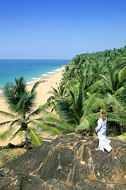 Woman looking over coconut palms to the beach, Kovalam, Kerala state, India, Asia