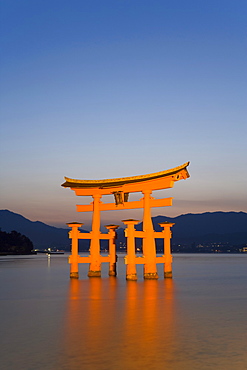 The vermillion coloured floating torii gate (O-Torii) (Grand Gate) of the Shinto shrine illuminated at dusk, Itsukushima (Itsuku-shima) shrine, UNESCO World Heritage Site, Miyajima, Hiroshima area, island of Honshu, Japan, Asia