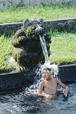 Boy under a water spout, WaterTemple, Bali, Indonesia