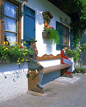 Figures carved on a bench on a decorative house front at Garmisch Partenkirchen in Bavaria, Germany, Europe