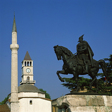 The statue of Skanderberg with the clock tower and minaret of the mosque beyond in Tirana, Albania, Europe